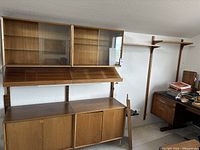 Overall view of assembled modular wall shelving system including cabinets, slanted shelves, rails and floating shelves