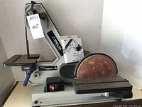 Full view of the Delta ShopMaster belt and disc sander showing the sanding belt, disc sander with flat worktable, and the machine base with power switch.