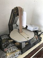 View of the full sander showing the sanding belt and disc with steel wool pads nearby.