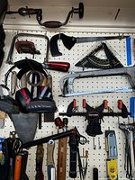 Manual hand brace drill, clamps, angle finder, speed square, screwdrivers, trowel on pegboard