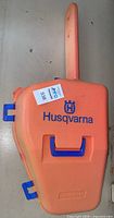 Closed orange Husqvarna branded hard plastic case with blue latches