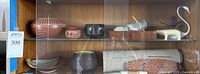 Shelf with assorted ceramics, sculptures and textiles on two glass shelves