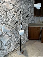 Full view of floor lamp showing three adjustable arms, white conical shades, chrome body and round white marble base