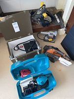 Overview of six power tools including Makita finishing sander in case, Craftsman palm sander, Ridgid and Porter+Cable belt sanders, Black & Decker finishing sander, and Sharper Image air compressor/inflator