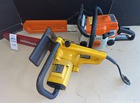 Both chainsaws with blade protectors on white surface