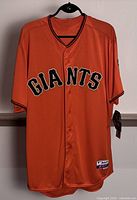 Front view of bright orange San Francisco Giants baseball jersey with GIANTS lettering and buttons down center.