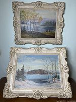 Two framed acrylic landscape paintings on board with ornate distressed white floral frames, displayed one above the other.