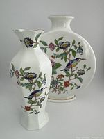 Photo of both Aynsley vases together showing round disk vase and octahedral vase side by side with floral and bird designs.