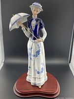 Front view of KPM porcelain figurine of a woman holding a parasol, standing on a wooden base.