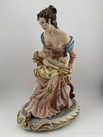 Front view of the Capodimonte Sonia porcelain figurine showing the woman in pink dress holding the child.
