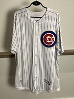 Front view of white Chicago Cubs pinstripe baseball jersey with Cubs logo patch on chest