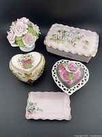 Front view showing entire lot of five china items: floral bouquet, two heart-shaped trinket boxes, small tray, larger floral trinket box.