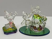Photo showing Mickey Mouse Fantasia crystal figurine with colorful octagonal base and Snow White with Happy crystal figurine on green oval base