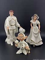 Photo showing all three figurines of Snow White, The Prince, and Dopey against a black background