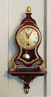 Front view of burgundy and gold clock hanging on wall