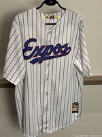 Front view of white pinstripe Montreal Expos jersey with 'Expos' wordmark in blue and red.
