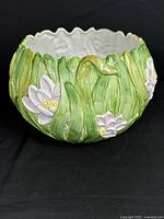 Front side view of Fitz and Floyd ceramic planter showing detailed green leaves and white flower accents.