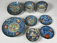 Overview of all 18 pieces showing bowls and plates with various traditional Japanese floral and bird patterns.