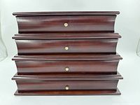 Front view of dark wood 4 drawer jewellery box showing brass knobs and wood finish.