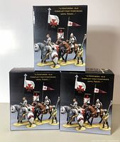 Three boxed King & Country figures showing front packaging with image of assembled figures and medieval flags.