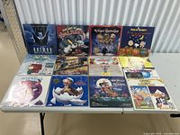 Assorted cartoon LaserDiscs displayed on a table including Batman: Mask of the Phantasm, The Art of Tom & Jerry, My Neighbors the Croods, Peanuts Classic, Tex Avery Screwball Classics, The Land Before Time and All Dogs Go to Heaven, plus additional titles visible.