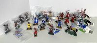 Photo showing entire medieval knight figurine set of 27 plastic figures in various colors and stances, standing and mounted on horses.