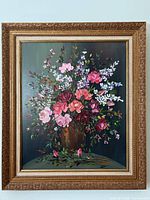 Full view of the oil painting showing a colorful bouquet of various flowers in a brown vase with dark green background, framed in an ornate gold frame.