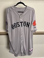 Front view of gray button-up Boston Red Sox jersey with BOSTON text, Red Sox logo on left sleeve, World Series Champions patch on right sleeve, and Majestic tag visible on bottom left.