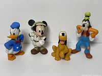 Front view of all four figurines - Donald Duck, Mickey Mouse in safari outfit, Pluto, and Goofy standing