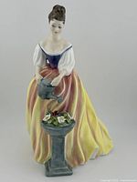 Full front view of the Royal Doulton Alexandra figurine showing the woman in yellow and red skirt with watering can and flower pedestal.