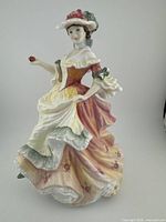 Front view of Royal Doulton porcelain figurine showing woman in Victorian dress holding a rose.