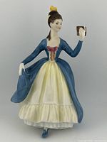 Front view of the figurine showing the full dress, facial details, and book held in hand.