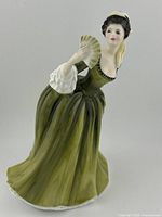 Front side view of the Royal Doulton Simone porcelain figurine showing the woman in a green dress holding a fan.