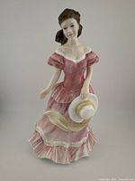 Front view of the Royal Doulton Amy HN 3854 figurine in pink dress holding white hat.