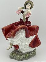 Front angled view of Royal Doulton Cheryl porcelain figurine in flowing layered dress and bonnet.