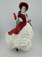 Front view of Royal Doulton Victorian Christmas porcelain figurine in red and white dress with bonnet.