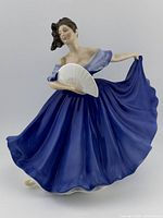 Front angle showing the woman in blue dress holding a white fan and skirt