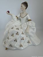 Front and side views of Royal Doulton porcelain figurine 'My Love' HN 2339 in white dress with gold floral accents and holding small red flowers.