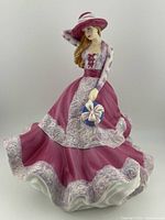 Front view of Royal Doulton figurine showing detailed pink dress, hat and parasol.