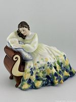 Front side view of the Royal Doulton Solitude HN 2810 figurine showing the woman reading on the chaise lounge.