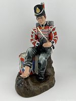 Front side view of Royal Doulton Drummer Boy figurine showing seated figure in detailed uniform and drum.