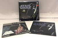 Front view of three Star Wars Trilogy laserdiscs with distinctive Darth Vader and classic poster art on sleeves showing THX and widescreen specialty editions.