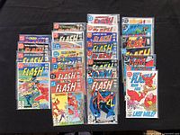 Top view of 25 comics arranged on black table, showing covers of The Flash issues with colorful artwork including cover titles and characters.