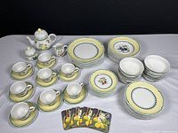 Overall view of teapot, sugar bowl, creamer, cups on saucers and stacks of plates and bowls