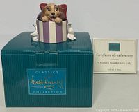 Photo of the figurine placed on top of its box with certificates alongside.