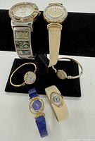 Overview of five watches arranged on display stand showing different styles and bands