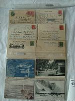 Top view of ten antique postcards arranged in two columns, showing a variety of stamps and scenic photographs including Niagara Falls and tents by a river.