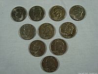 All 10 Eisenhower silver dollars showing front profile of Eisenhower laid out in rows on a pale surface.