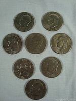 Top side (obverse) view of eight Eisenhower silver dollar coins showing President Eisenhower's profile.