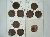 Nine Lincoln pennies spanning years 1925, 1927, 1935 with mint marks P, D, and S arranged on white cards, including a shiny newer penny.